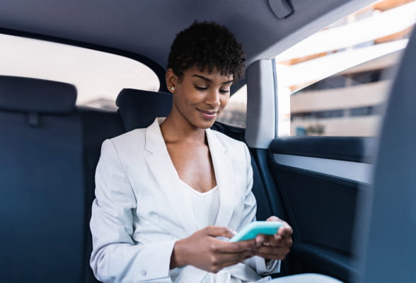 Professional using a smartphone in a car, highlighting StoneX Wealth Management's advanced platforms and technology for efficient account management