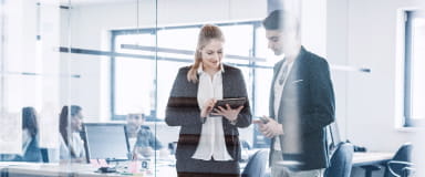Two colleagues discussing work on a tablet, reflecting StoneX Wealth Management's bespoke solutions tailored to clients' specific needs