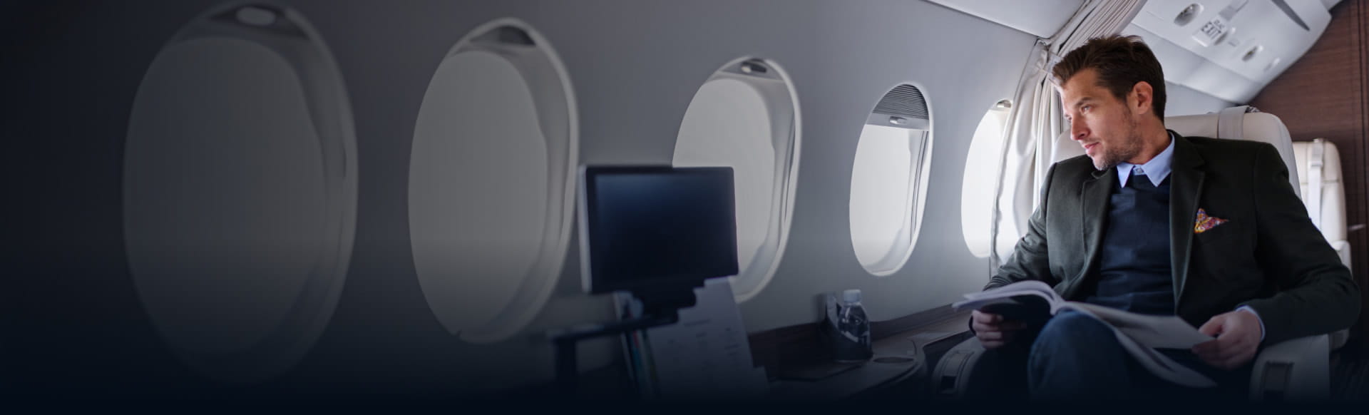 Man reading on a private jet, illustrating StoneX Wealth Management's customized solutions for international private clients