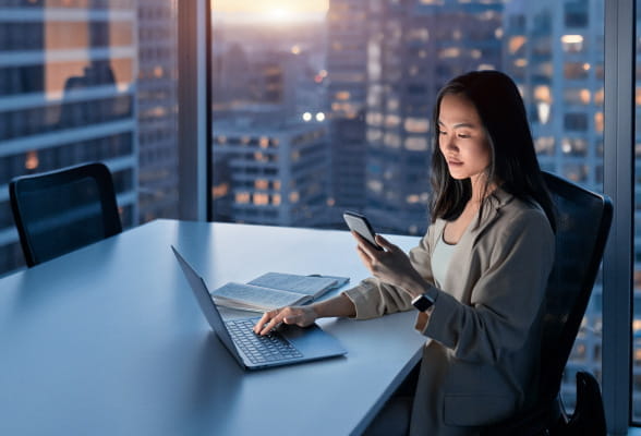 Financial professional using a smartphone and laptop, reflecting StoneX Wealth Management's technology solutions for business integration