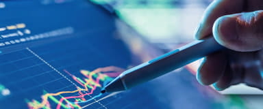 Hand with stylus analyzing market data, representing StoneX Pro's bespoke liquidity solutions.